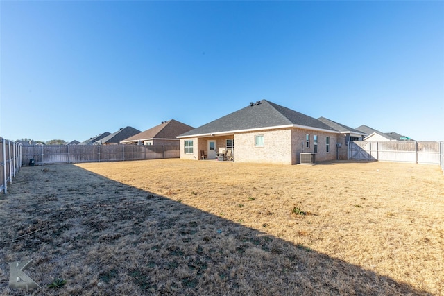 back of house with a yard, brick siding, cooling unit, and a fenced backyard