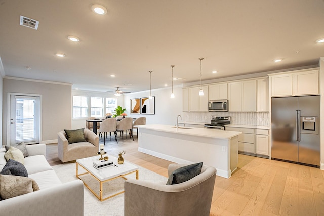 living area with light wood-style flooring, visible vents, crown molding, and recessed lighting