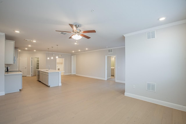 kitchen with visible vents, light countertops, a sink, and a center island with sink