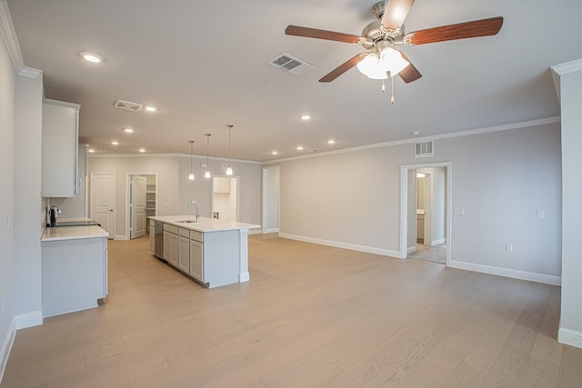 kitchen with a center island with sink, visible vents, light countertops, and a sink