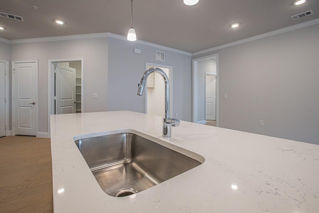 kitchen with hanging light fixtures, a sink, visible vents, and crown molding