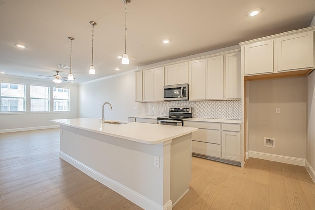 kitchen featuring decorative light fixtures, stainless steel appliances, a sink, light countertops, and a center island with sink