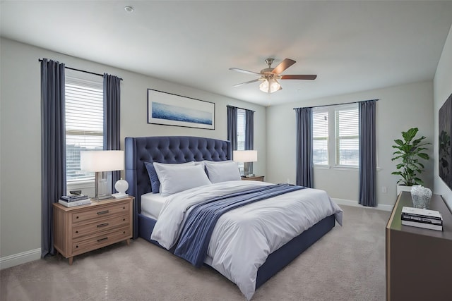 bedroom featuring light carpet, a ceiling fan, and baseboards