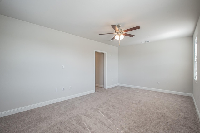 spare room with ceiling fan, visible vents, light colored carpet, and baseboards