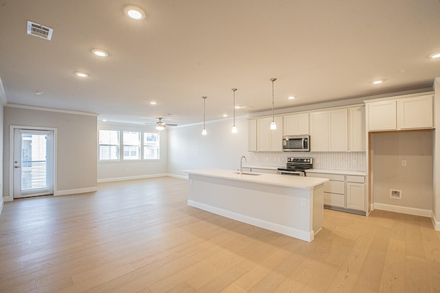 kitchen with a center island with sink, stainless steel appliances, light countertops, open floor plan, and a sink