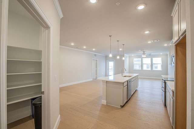 kitchen featuring stainless steel appliances, light countertops, open floor plan, a kitchen island with sink, and a sink