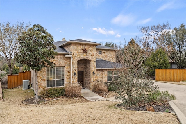 view of front of property with central AC, fence, stone siding, driveway, and a chimney