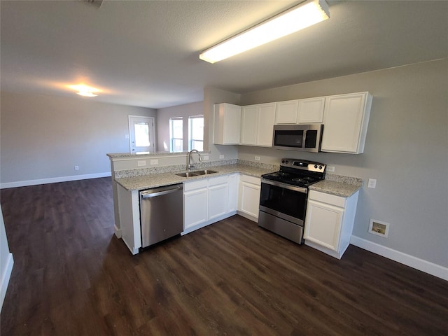 kitchen with baseboards, white cabinets, a peninsula, stainless steel appliances, and a sink