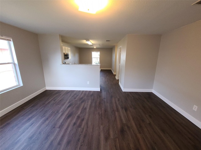 unfurnished room with dark wood finished floors, visible vents, and baseboards