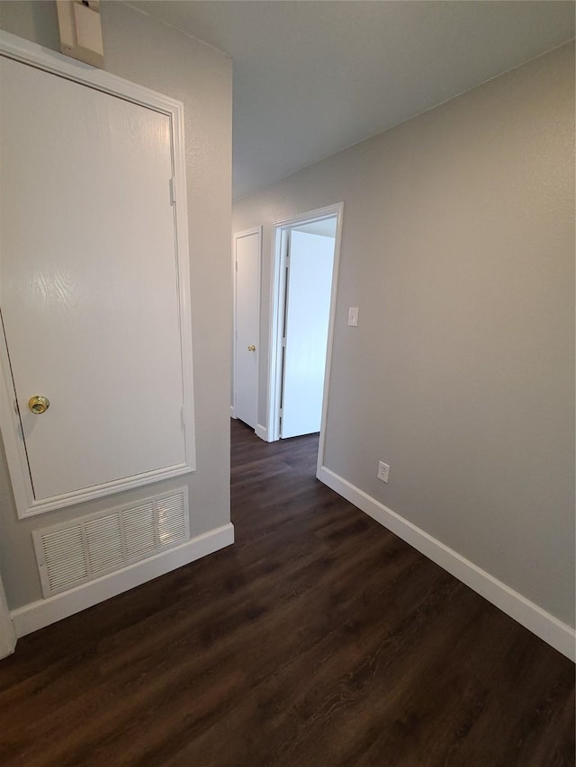 empty room with baseboards, visible vents, and dark wood-style flooring