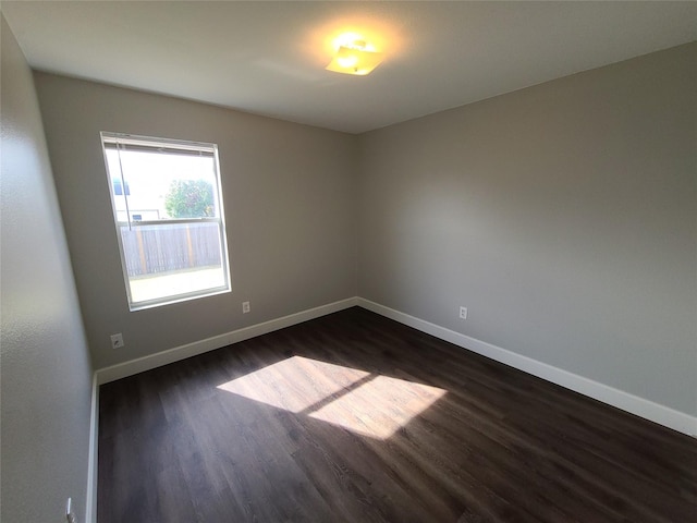 unfurnished room featuring baseboards and dark wood-type flooring