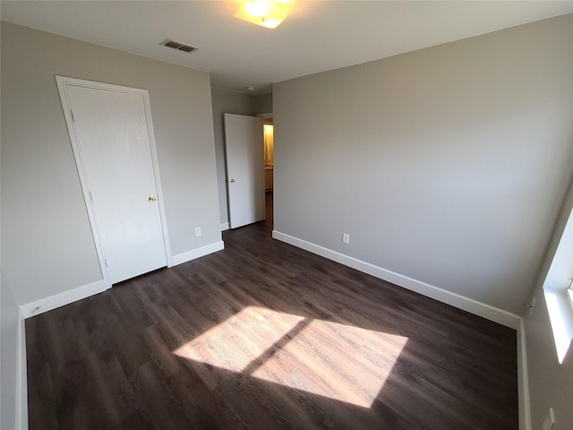 unfurnished bedroom featuring visible vents, baseboards, and dark wood-type flooring