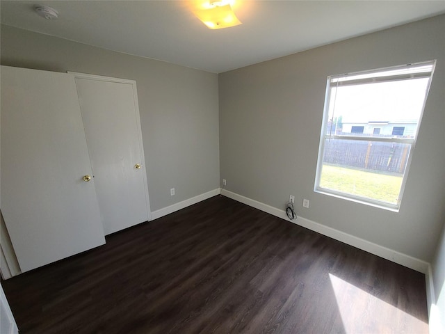 unfurnished bedroom with dark wood-style flooring and baseboards