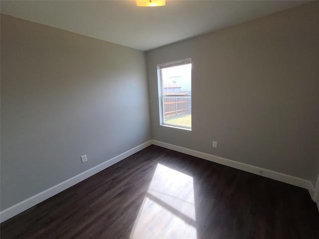 empty room featuring dark wood-style floors and baseboards