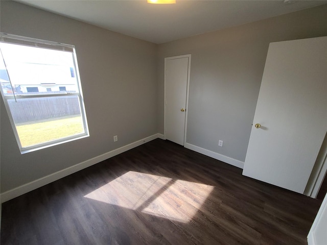 unfurnished room with dark wood-style floors and baseboards