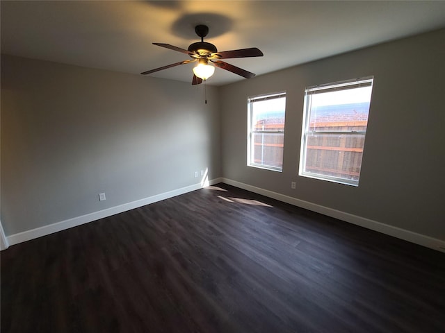 spare room with dark wood-style flooring, ceiling fan, and baseboards