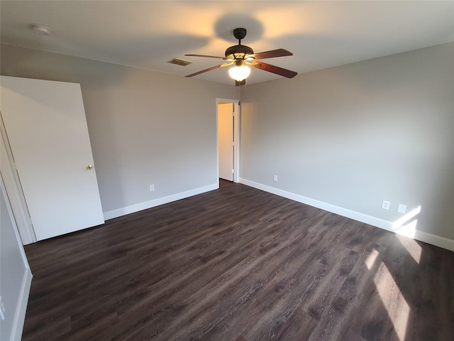 spare room with visible vents, dark wood finished floors, a ceiling fan, and baseboards