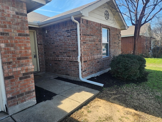 exterior space featuring a shingled roof and brick siding