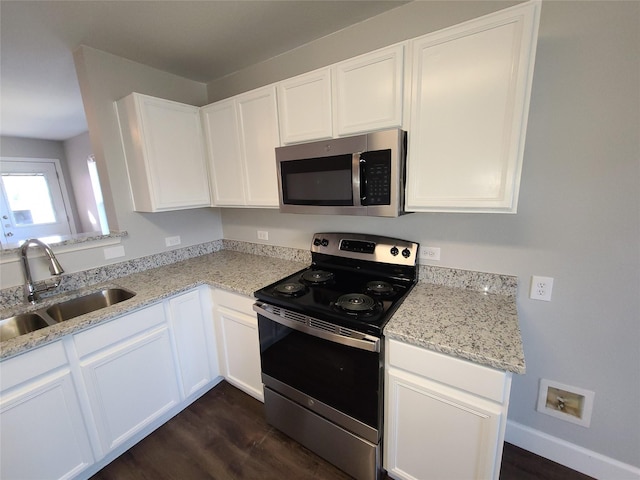 kitchen featuring light stone counters, dark wood-style flooring, stainless steel appliances, white cabinets, and a sink