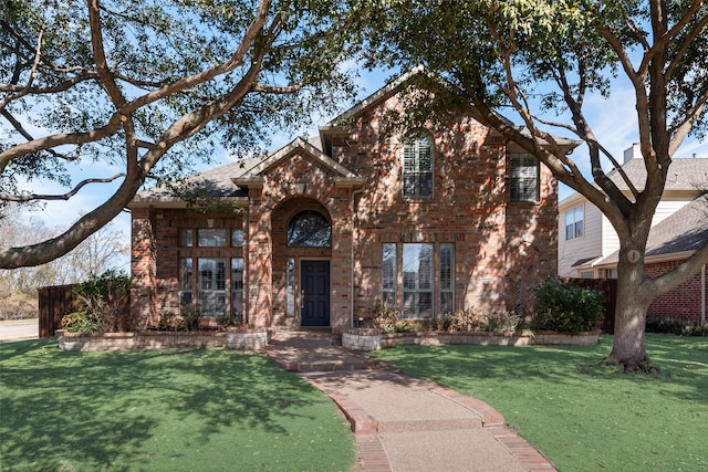 traditional-style home featuring brick siding and a front yard