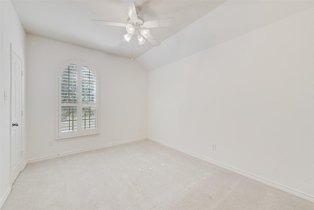 spare room with light colored carpet, vaulted ceiling, baseboards, and ceiling fan