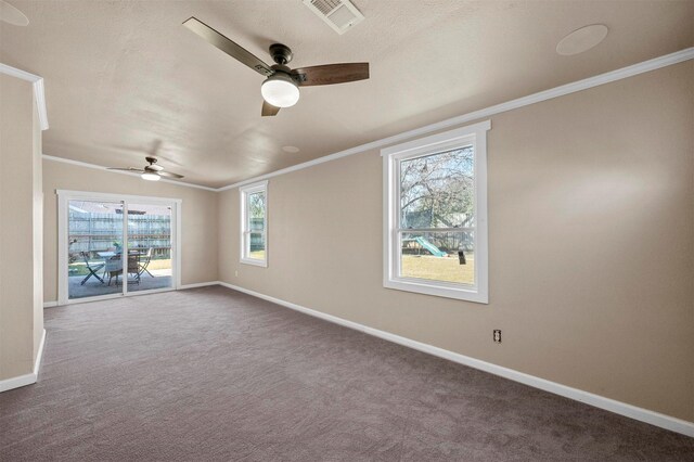 empty room featuring ceiling fan, visible vents, baseboards, dark colored carpet, and crown molding