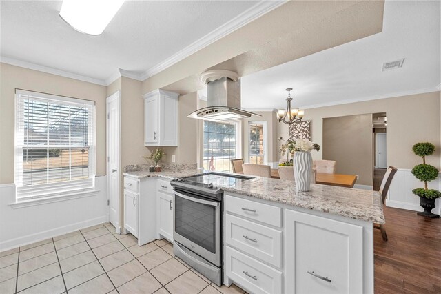 kitchen with visible vents, a peninsula, ventilation hood, stainless steel range with electric stovetop, and white cabinetry