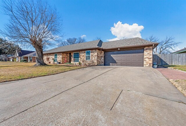 ranch-style house with a garage, concrete driveway, fence, a front lawn, and brick siding