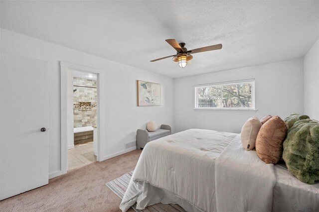 bedroom featuring light carpet, connected bathroom, ceiling fan, a textured ceiling, and baseboards