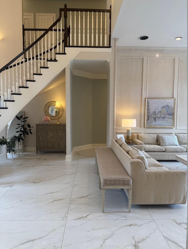 unfurnished living room featuring stairs, marble finish floor, a towering ceiling, and crown molding