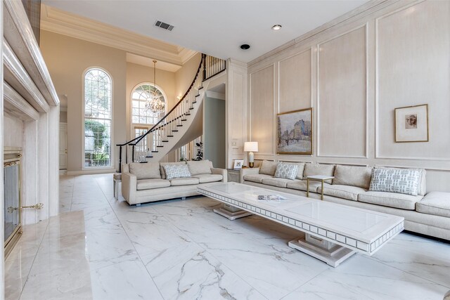 living area with stairway, a decorative wall, visible vents, and marble finish floor