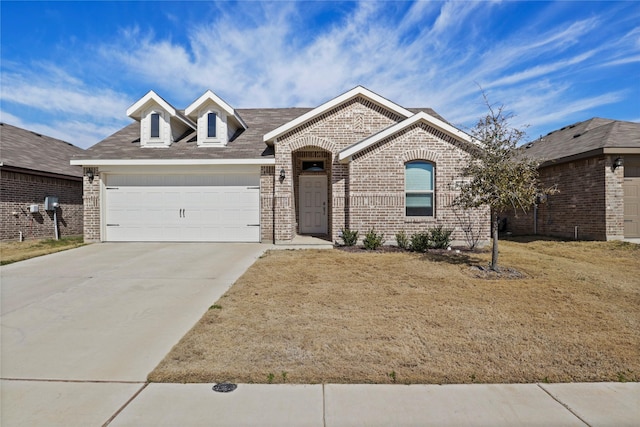 french country style house with a garage, driveway, brick siding, and a front yard