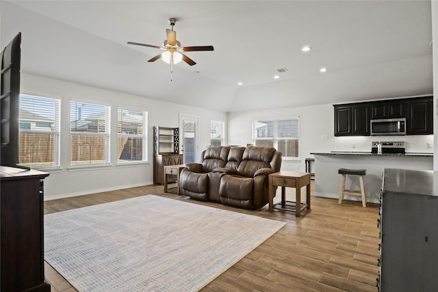 living area with light wood-type flooring, plenty of natural light, lofted ceiling, and recessed lighting