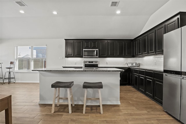 kitchen featuring stainless steel appliances, a center island, and visible vents