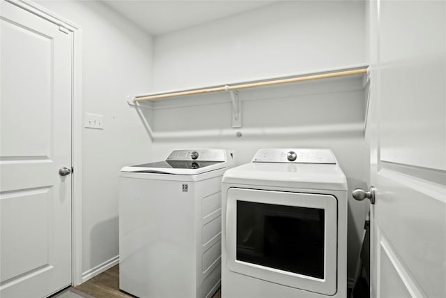 clothes washing area with dark wood-style floors, laundry area, and washer and dryer