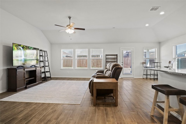 living area featuring lofted ceiling, ceiling fan, visible vents, and wood finished floors