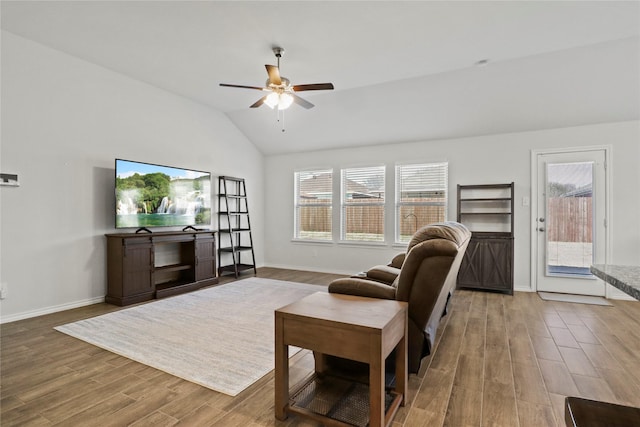 living area with vaulted ceiling, plenty of natural light, wood finished floors, and a ceiling fan