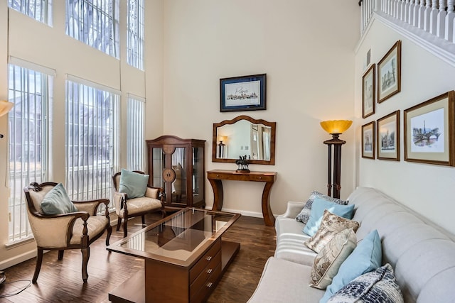 living area featuring dark wood-style flooring, baseboards, and a high ceiling