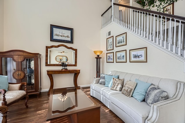 living room with a towering ceiling, baseboards, visible vents, and dark wood finished floors