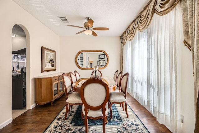 dining room featuring dark wood-style floors, arched walkways, visible vents, ceiling fan, and a textured ceiling