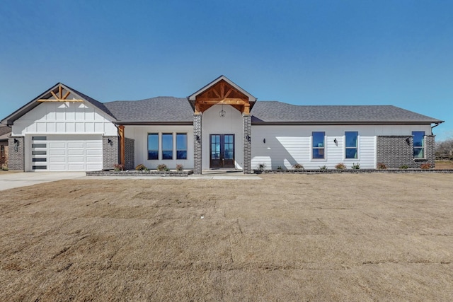 view of front of property featuring a garage, driveway, a front lawn, and a shingled roof