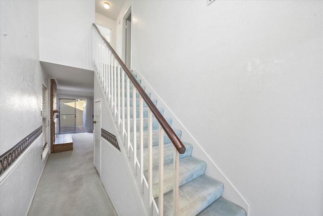 stairway featuring carpet floors and a high ceiling