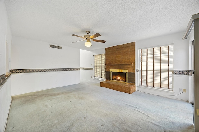 unfurnished living room with a brick fireplace, visible vents, light carpet, and a textured ceiling