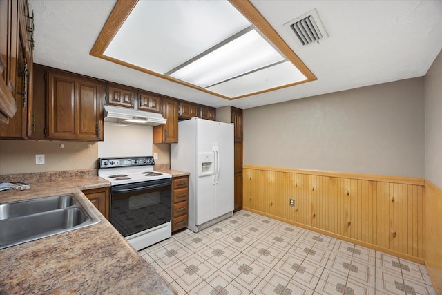 kitchen with white appliances, visible vents, wainscoting, under cabinet range hood, and a sink