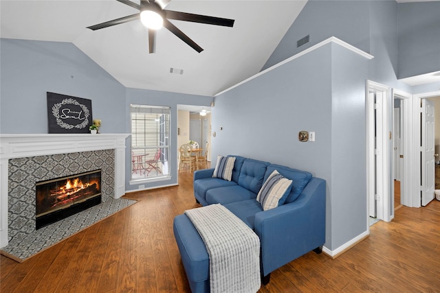 living area with ceiling fan, a tile fireplace, wood finished floors, and visible vents