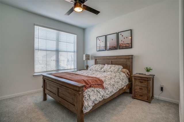 bedroom featuring light colored carpet, baseboards, and a ceiling fan