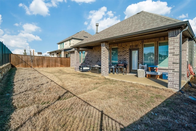 back of house featuring a fenced backyard, a patio area, and brick siding