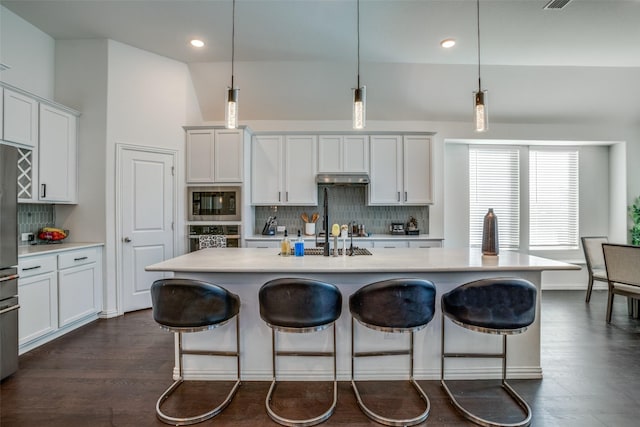kitchen featuring tasteful backsplash, light countertops, a kitchen breakfast bar, and stainless steel appliances