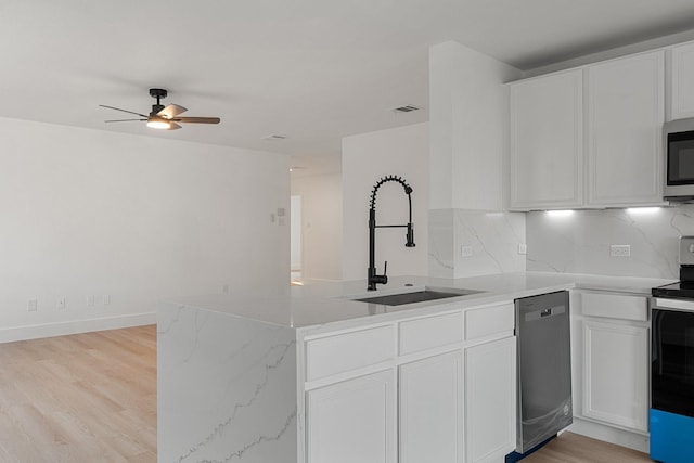 kitchen featuring a peninsula, appliances with stainless steel finishes, white cabinets, and a sink