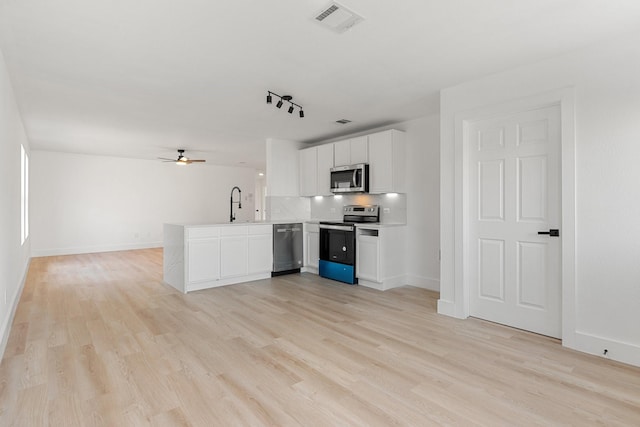 kitchen with white cabinets, appliances with stainless steel finishes, open floor plan, a peninsula, and light countertops